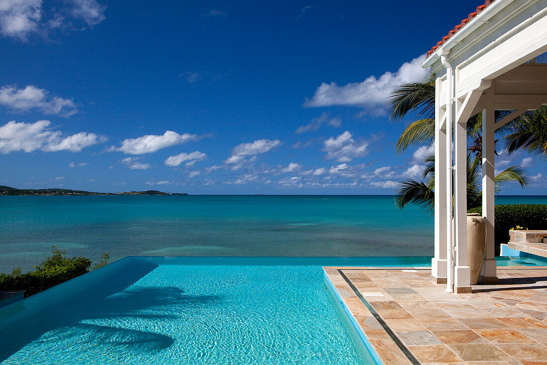 Blick auf das Meer von einem Infinity-Pool und einem Bungalow. Antigua, Westindische Inseln