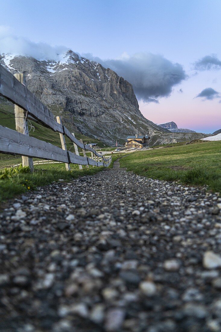 Fußweg in Richtung majestätischer Sassopiatto und Hütte bei Sonnenuntergang, Alpe di Siusi / Seiser Alm, Dolomiten, Südtirol, Italien