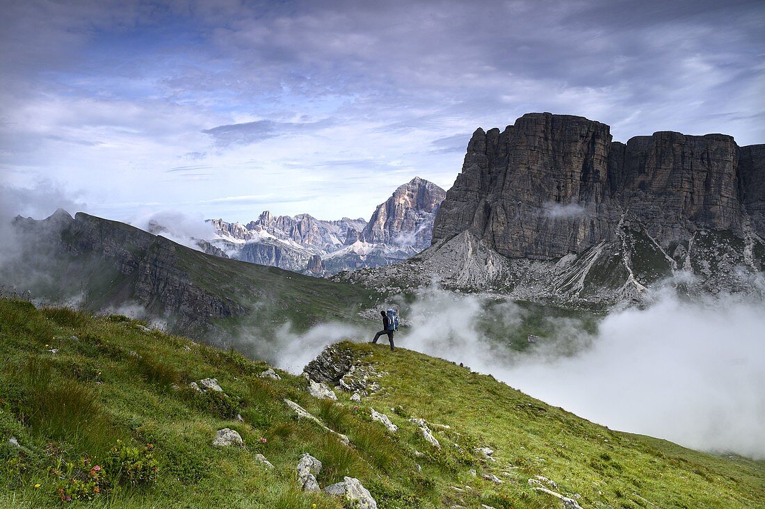 Wanderer bewundern das Panorama in den frühen Morgenstunden von den Hängen des Berges Mondeval, rechts der Lastoi di Formin, im Hintergrund die Tofana di Rozes und die Lagazuoi, die teilweise von Wolken bedeckt sind