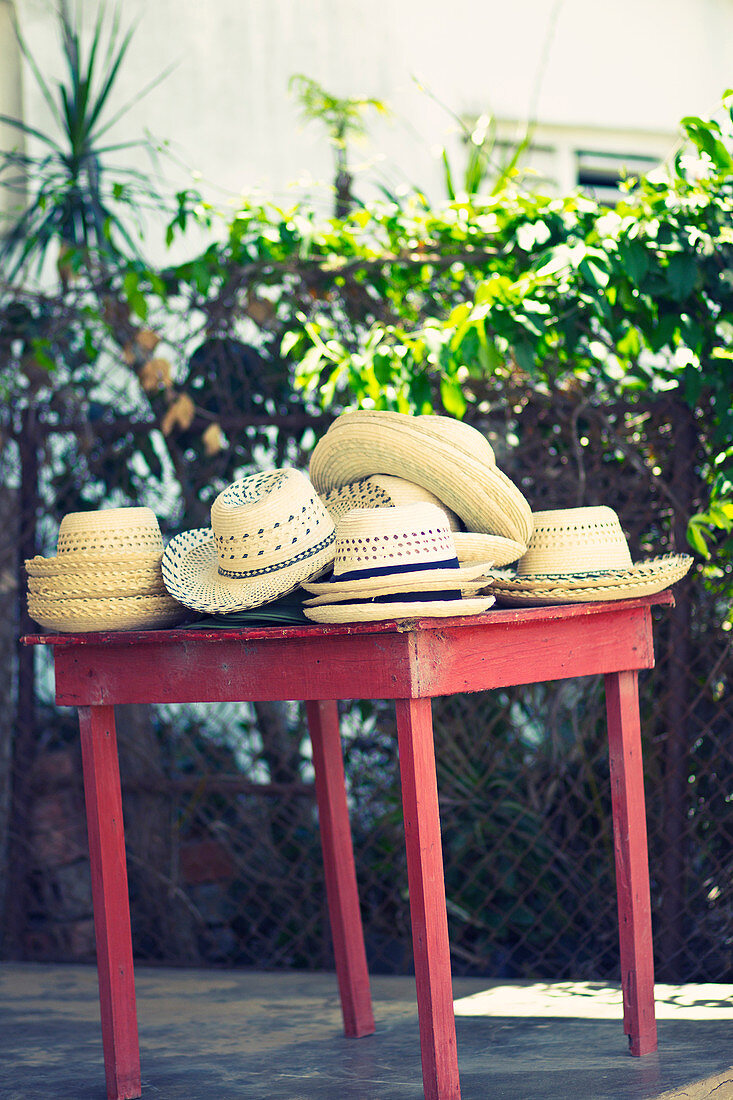 Braided straw hats on a red table in Viñales, Cuba