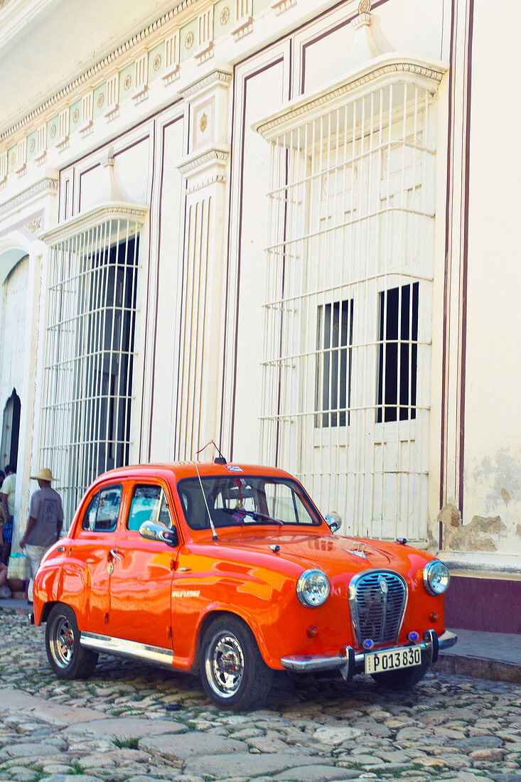 Classic red car in front of a white building in Trinidad, Cuba