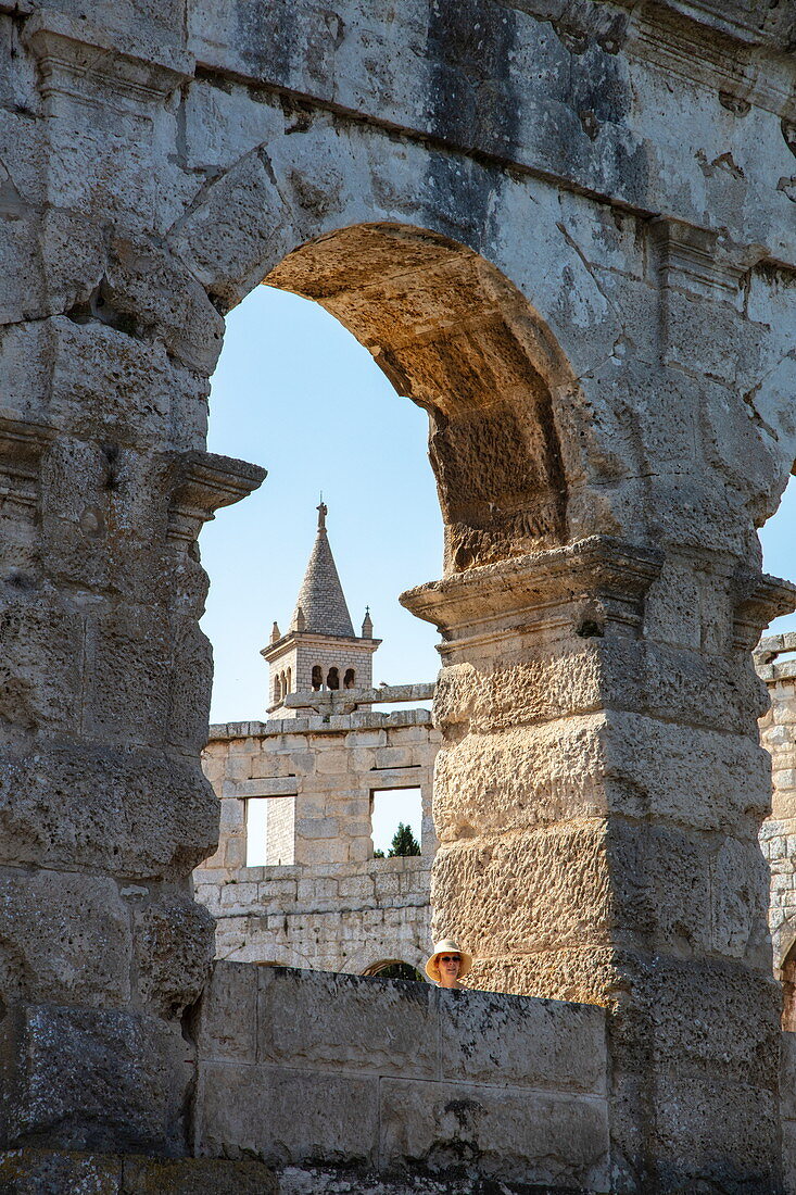 Church tower seen through archway of Roman amphitheater, Pula Arena, Pula, Istria, Croatia, Europe