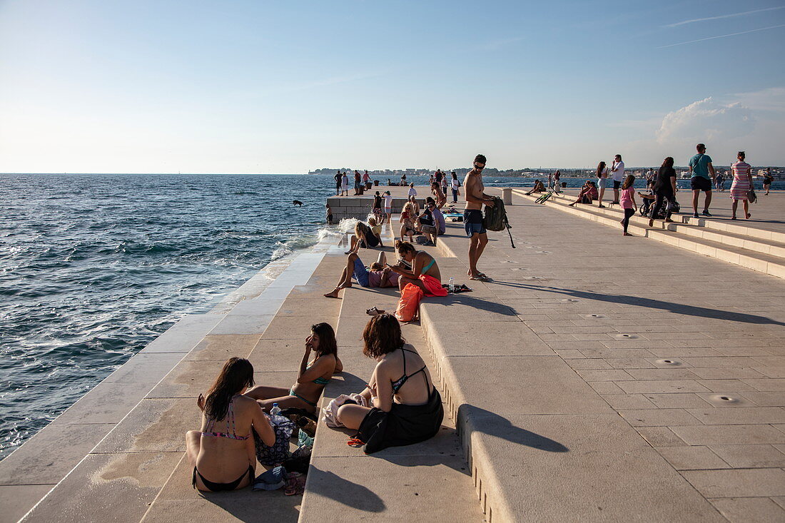 Menschen entspannen sich an der Strandpromenade und lauschen der Meeresorgel, Zadar, Zadar, Kroatien, Europa