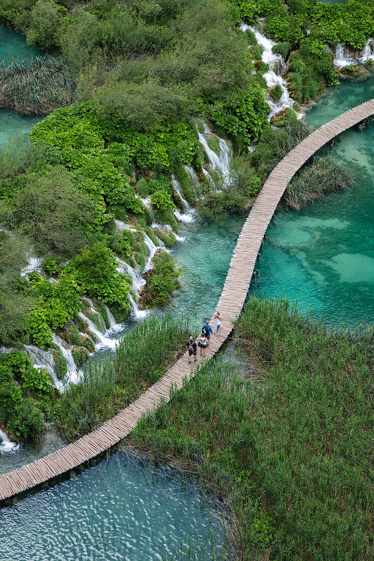Blick auf Menschen auf Holzbohlenpfad über Pool mit Wasserfällen, Nationalpark Plitvicer Seen, Lika-Senj, Kroatien, Europa