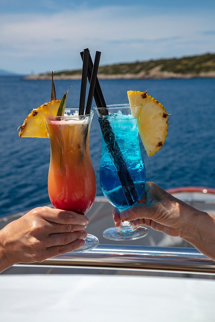Detail von zwei bunten Cocktails in den Händen von Passagieren an Bord von Kreuzfahrtschiff, Vis, Vis, Split-Dalmatien, Kroatien, Europa
