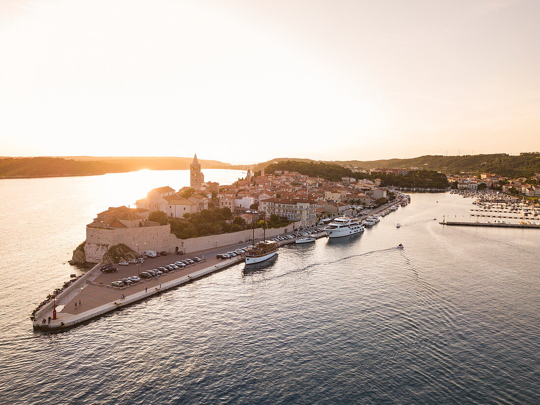 Luftaufnahme von Kreuzfahrtschiff und weiterer Boote die bei Sonnenuntergang an der Altstadt festgemacht haben, Rab, Primorje-Gorski Kotar, Kroatien, Europa