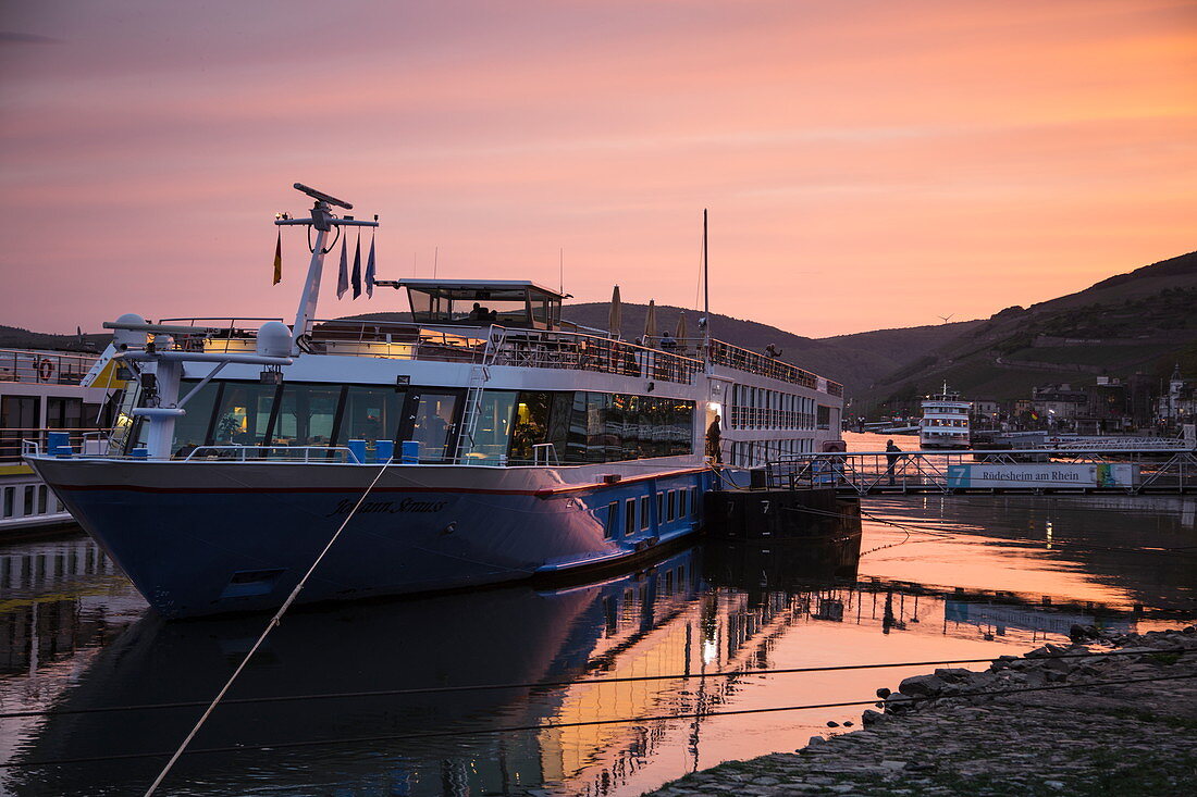 Flusskreuzfahrtschiff am Anleger während einer Kreuzfahrt auf dem Rhein bei Sonnenuntergang, Rüdesheim am Rhein, Hessen, Deutschland, Europa