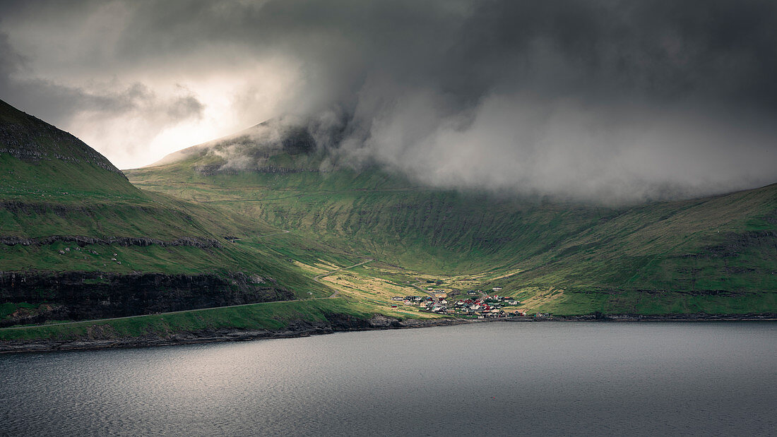 Gemeinde Funningur auf Insel Eysturoy unter dramatischen Wolken, Färöer Inseln\n