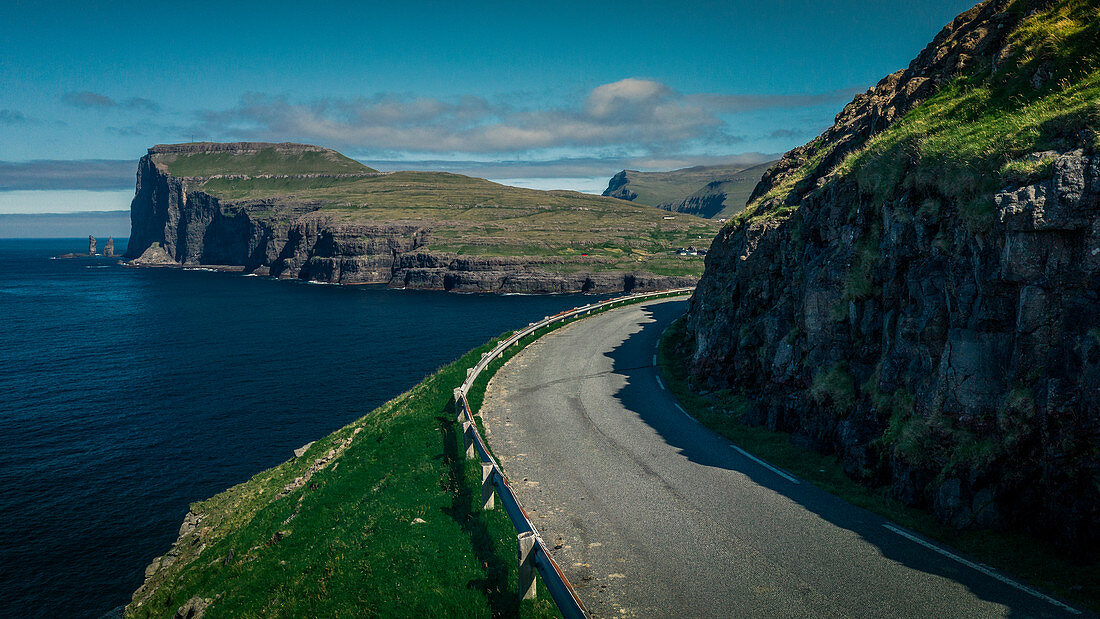 Road to the village of Tjørnuvík on Streymoy, with a view of Eysturoy Island in the daytime with sun and blue sky, Faroe Islands