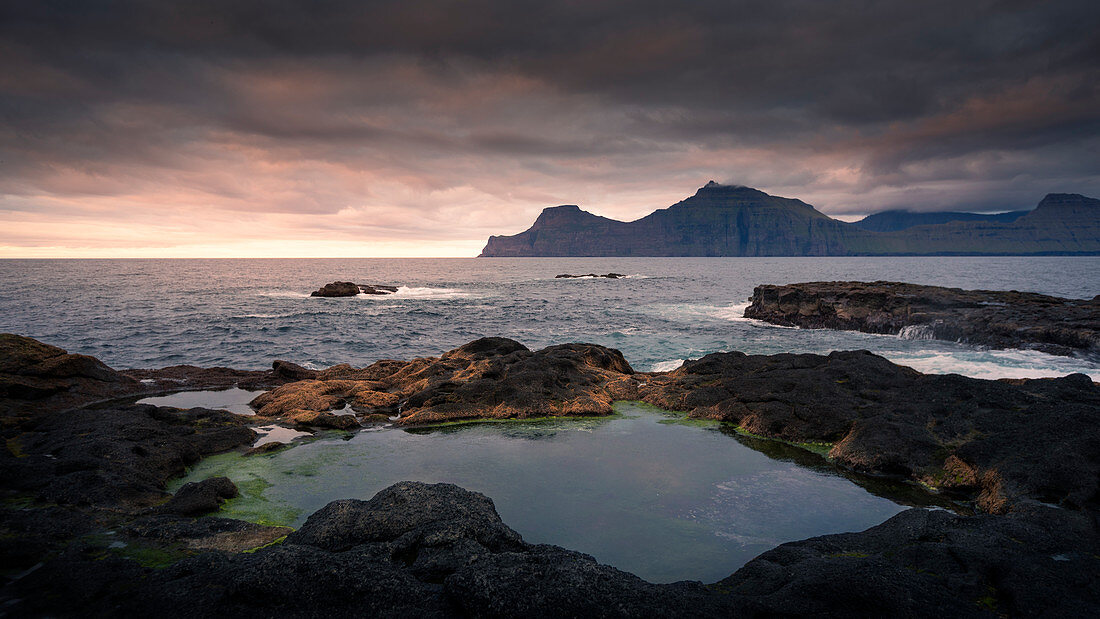 Wasserpools am Meer bei Gjogv im Sonnenuntergang mit Blick auf Kalsoy, Färöer Inseln\n