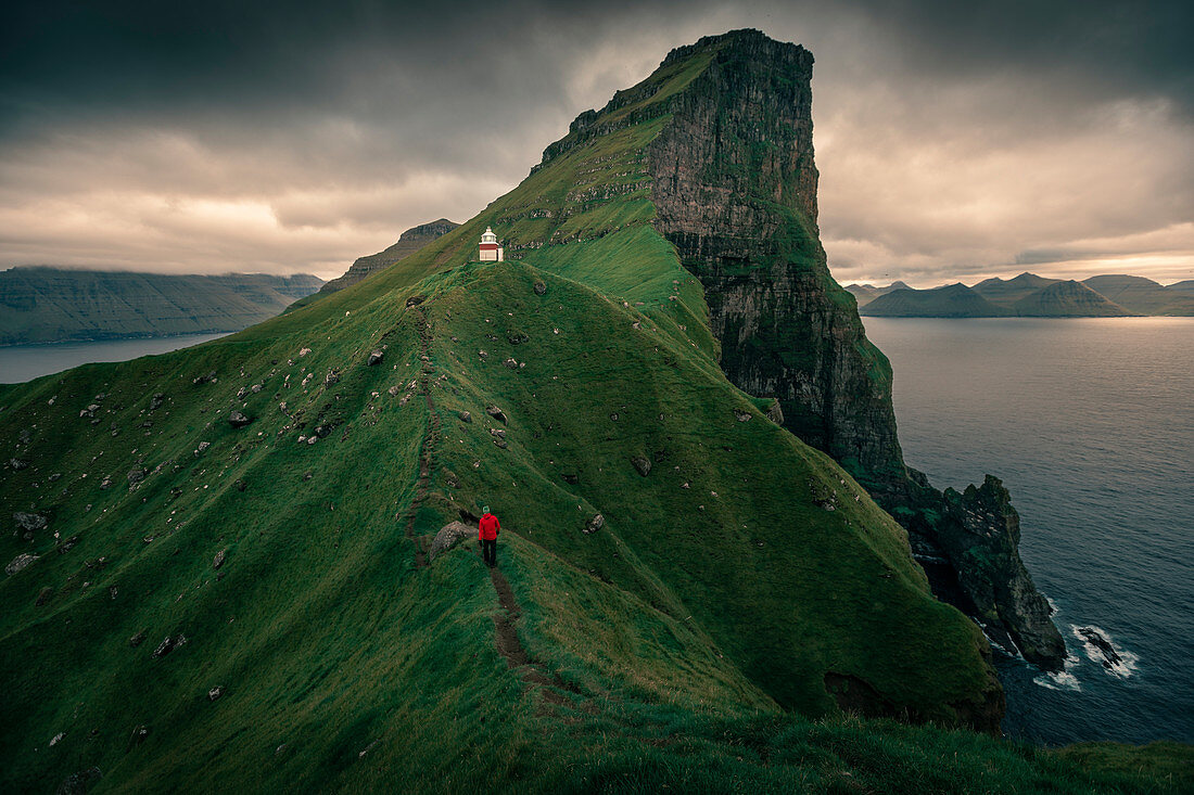 Man hikes to lighthouse on Kalsoy Island, Faroe Islands
