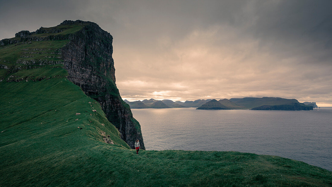 Frau wandert an Klippe der Insel Kalsoy, Färöer Inseln\n