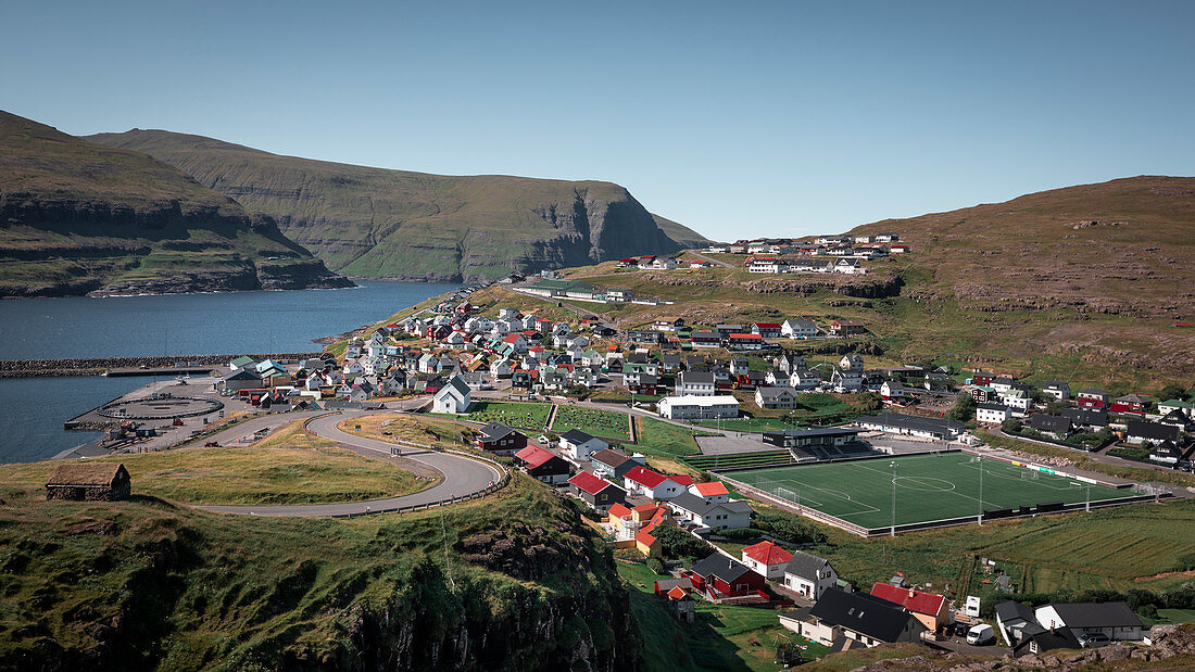 Dorf Eidi auf Eysturoy der Färöer Inseln bei Tag mit geschwungener Straße\n