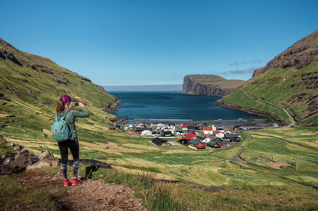Frau beim Wandern fotografiert Dorf Tjørnuvík auf Streymoy auf Färöer Inseln bei Tag\n