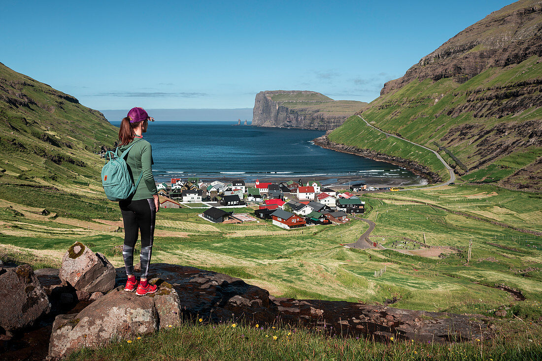 Woman hiking with a view of Tjørnuvík village on Streymoy on Faroe Islands by day