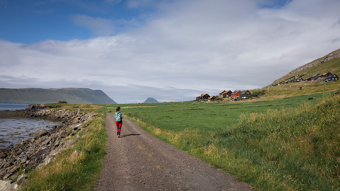 Frau wandert auf Weg im Dorf Kirkjubøur auf Streymoy, Färöer Inseln\n