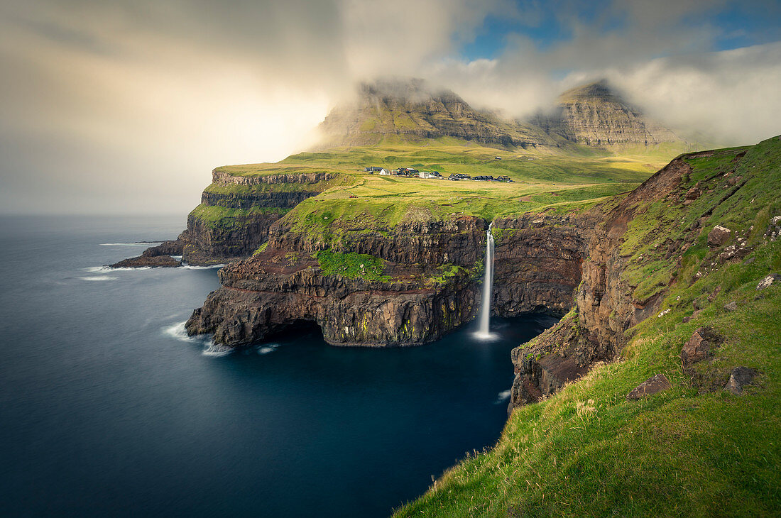 Wasserfall Múlafossur mit Dorf Gásadalur auf der Insel Vagar, Färöer Inseln\n