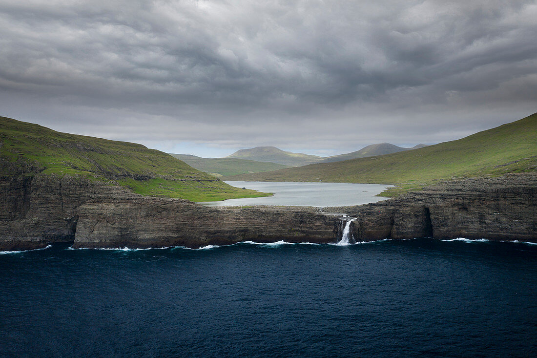 Küste, Wasserfall und Klippen bei Trælanípa auf der Insel Vagar, am See Leitisvatn, Färöer Inseln\n