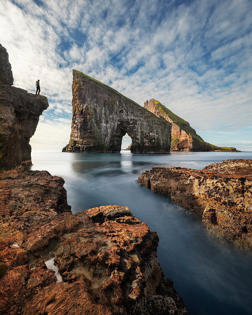 Person in front of Drangarnier rock formations on Vagar, Faroe Islands