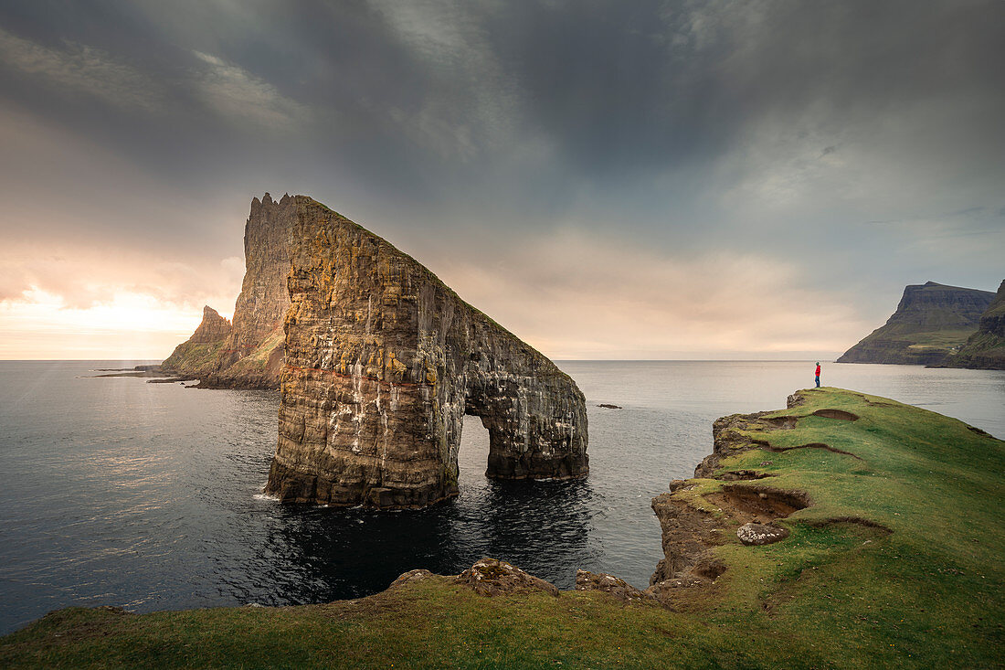 Person in sunset in front of Drangarnier rock formations on Vagar, Faroe Islands