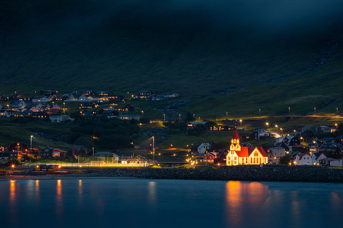 Beleuchtete Kirche bei Nacht im Dorf von Sandavágur auf der Insel Vagar, Färöer Inseln\n