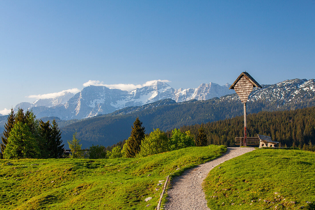 Holzkreuz mit Ausblick auf die Loferer Steinberge auf der Winklmoos Alm im Frühling, Tirol, Chiemgau, Bayern, Deutschland