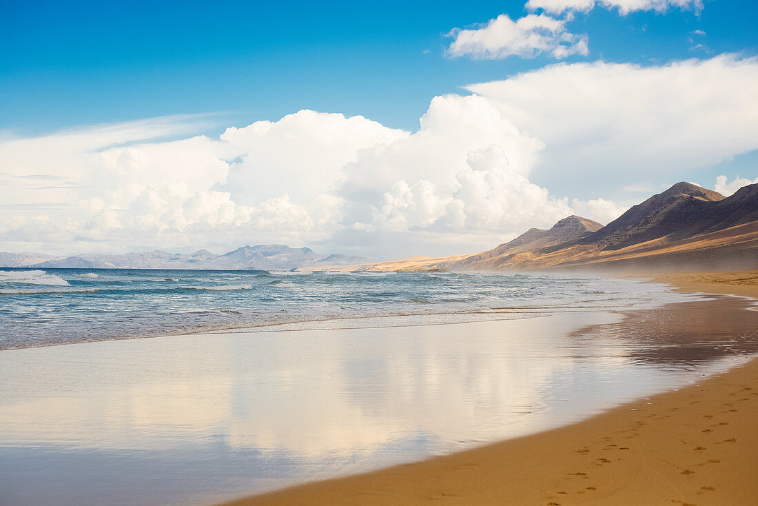 View along a sandy beach on Fuerteventura on a cloudy day.
