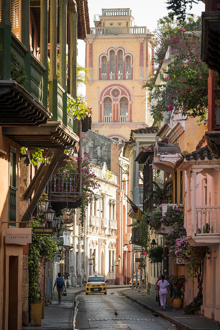 Blick entlang der engen Straße in die Altstadt, elegante historische Häuser mit Balkon und hohem Kirchturm