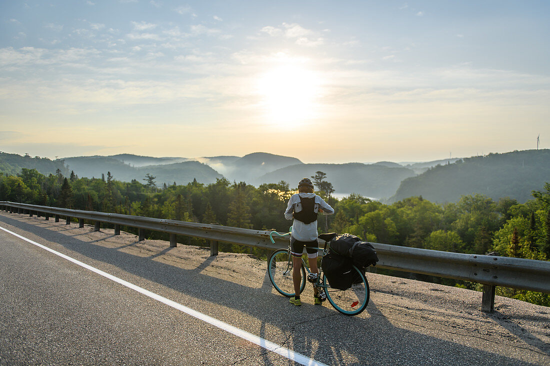 Cyclist stopping on road with scenic view, Ontario, Canada