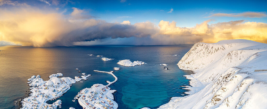 Brennender Himmel bei Sonnenaufgang über dem kalten Meer und Sorvaer-Dorf bedeckt mit Schnee, Soroya-Insel, Hasvik, Troms og Finnmark, Arktis, Norwegen, Skandinavien, Europa