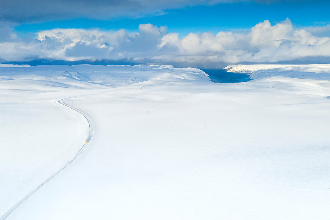 Aerial view of empty road towards Nordkapp (North Cape) crossing the landscape covered by deep snow, Troms og Finnmark, Norway, Scandinavia, Europe