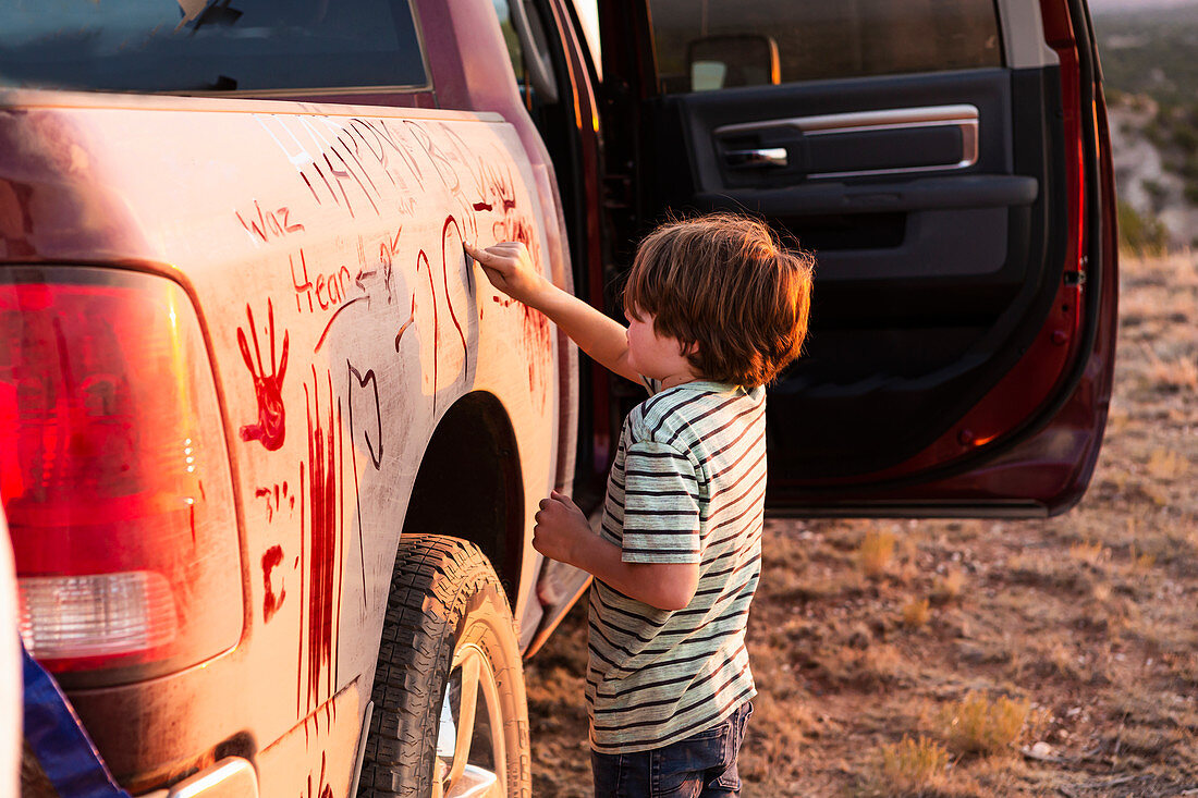 young boy writing on dirty pickup truck
