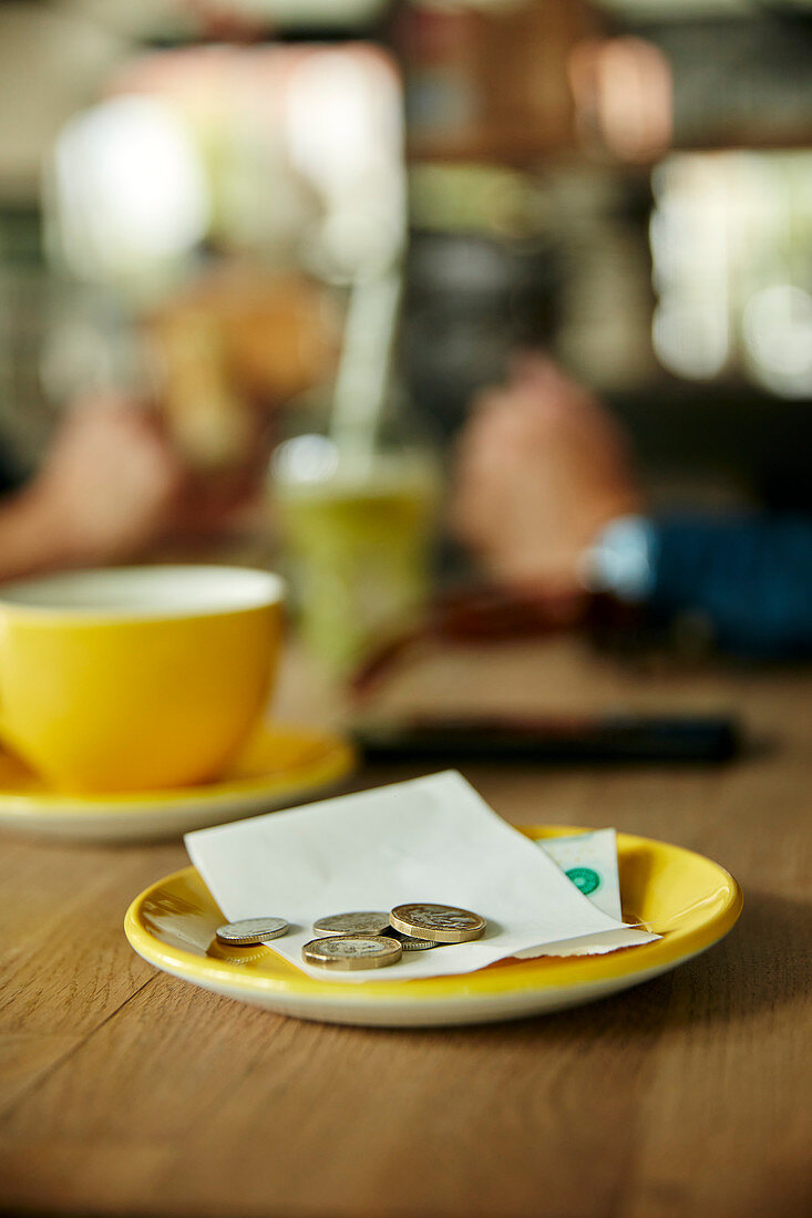 Geldmünzen und Rechnung auf einem Cafétisch