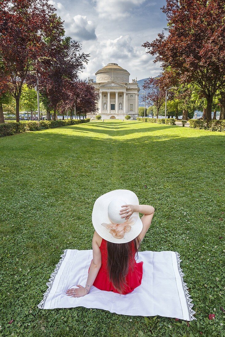 Eine Touristin, der auf Como Gärten sitzt, sieht ein Volta Tempeldenkmal (Tempio Voltiano), Como Stadt, Lombardei, Italien, Europa