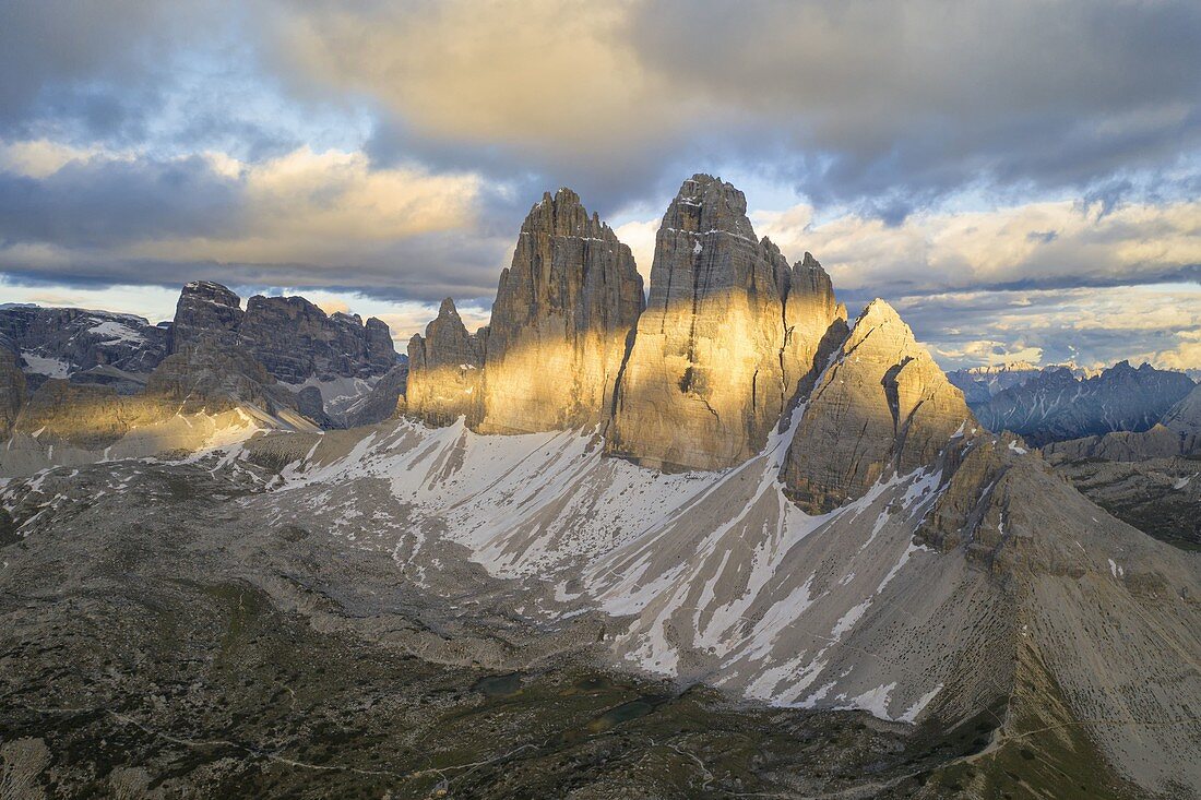 the majestic Tre Cime di Lavaredo, shot by a photographer with a helicopter during a sunset with warm light, Dolomiti, Unesco World Heritage Site, belluno province, Veneto district, Italy, Europe