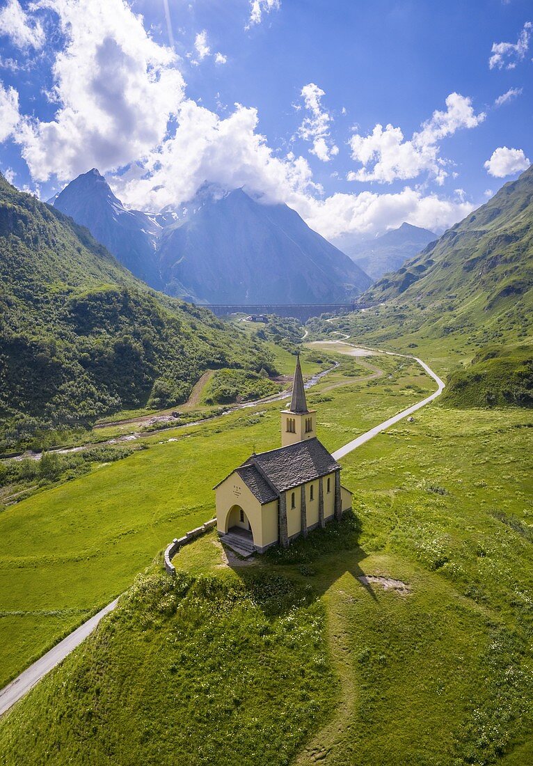 Aerial view of the Oratorio di Sant'Anna church, Riale and the Morasco lake and dam in summer. Formazza, Valle Formazza, Verbano Cusio Ossola, Piedmont, Italy.