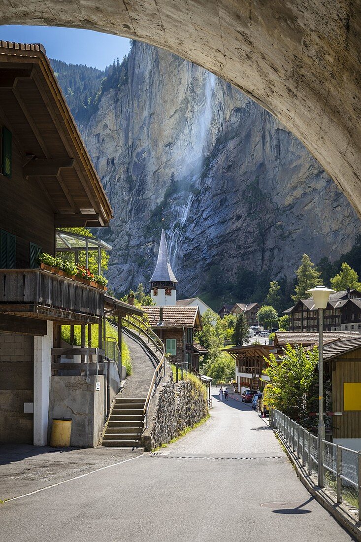 View of the church and Staubbach waterfall behind it in the town centre of Lauterbrunnen village. Lauterbrunnen, Canton of Bern, Switzerland, Europe.