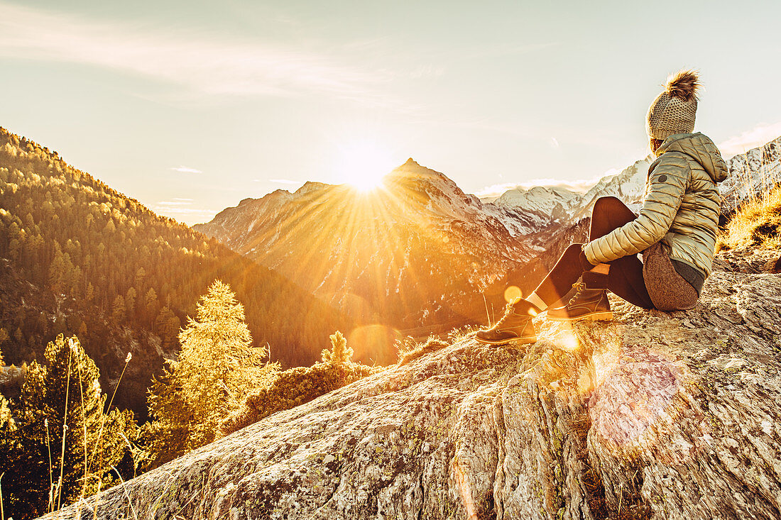 Woman sits on rocks in Maloja and enjoys the sunset, Engadin, Graubünden, Switzerland, Europe