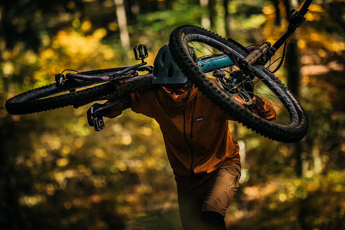 Mountain biker carries his bike through autumn forest, mountain biker, autumn, forest