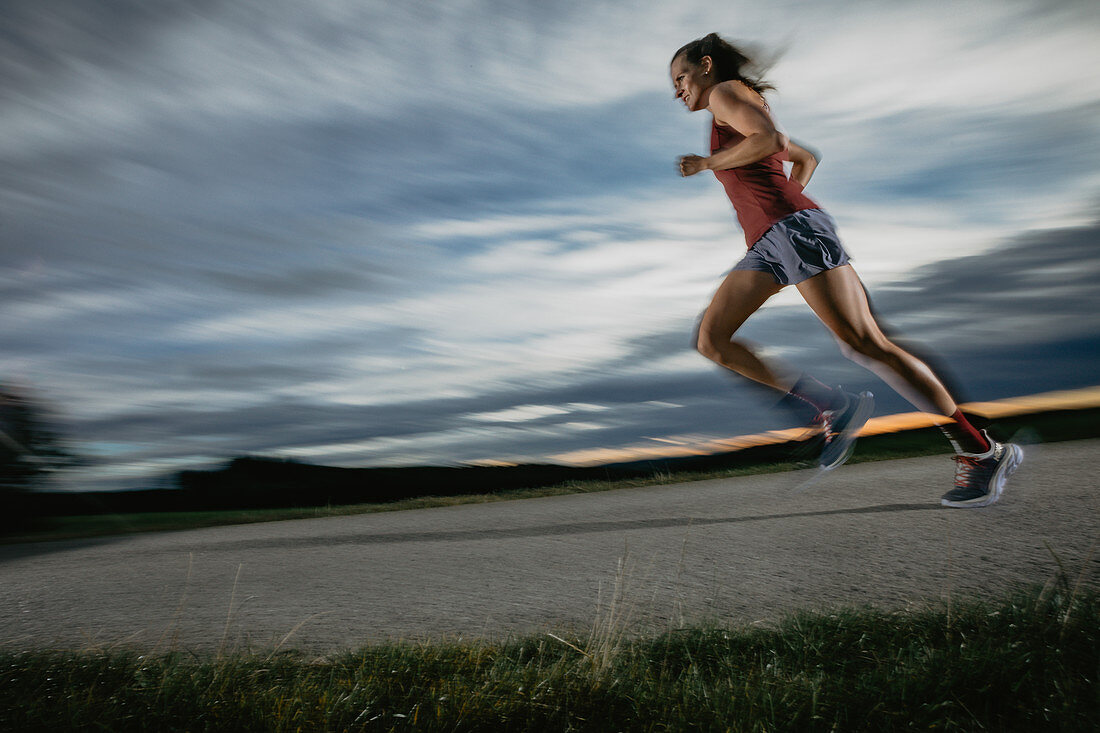 Woman runner runs on road in sunset, sport, forest