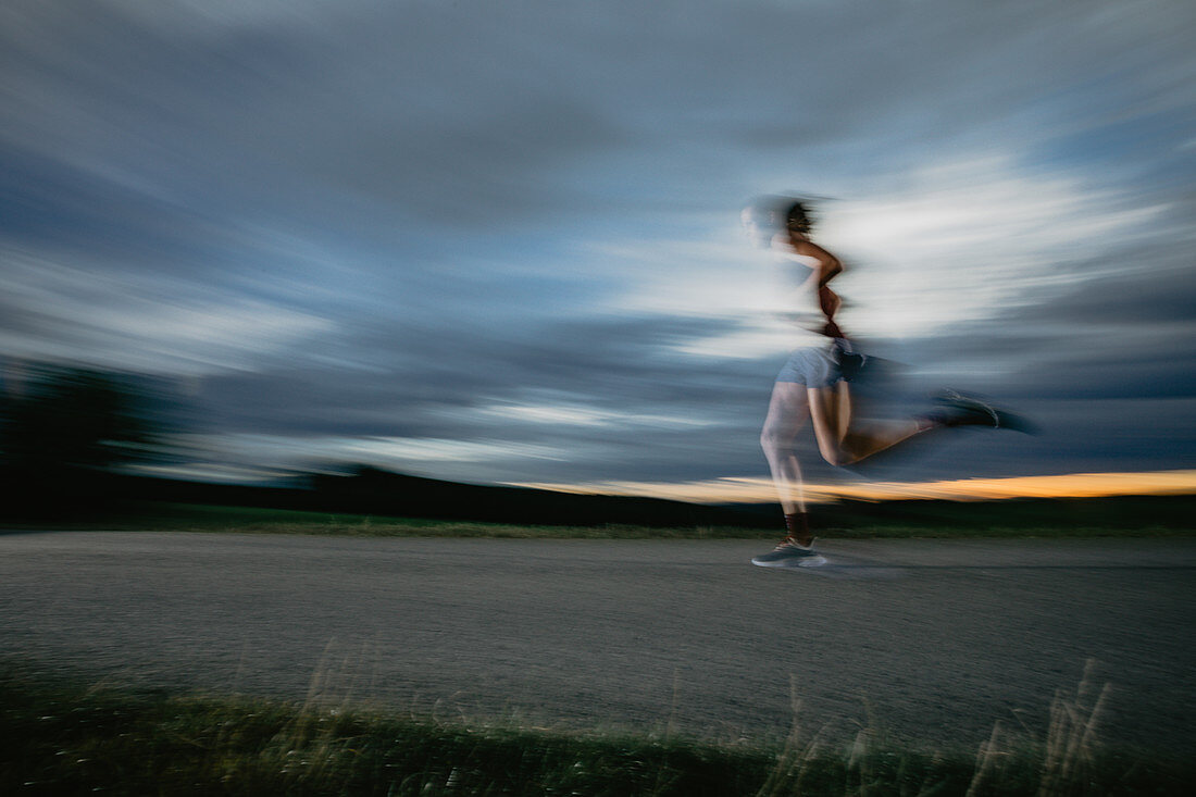 Läuferin läuft auf der Straße im Sonnenuntergang