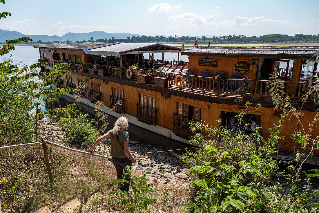 Frau steigt Weg hinab zu Flusskreuzfahrtschiff Mekong Sun auf Fluss Mekong, Houayxay (Huay Xai), Provinz Bokeo, Laos, Asien