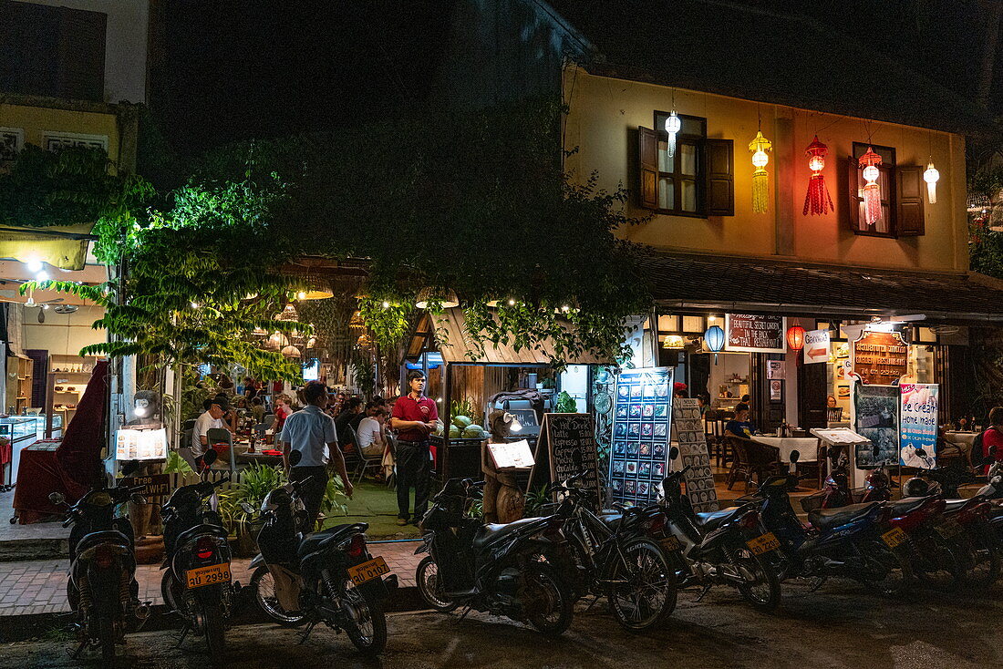 Mopeds stehen vor belebten Restaurant und Bar in der Sisavangvong Road (der Hauptstraße) Gästen im Außenbereich, Luang Prabang, Provinz Luang Prabang, Laos, Asien