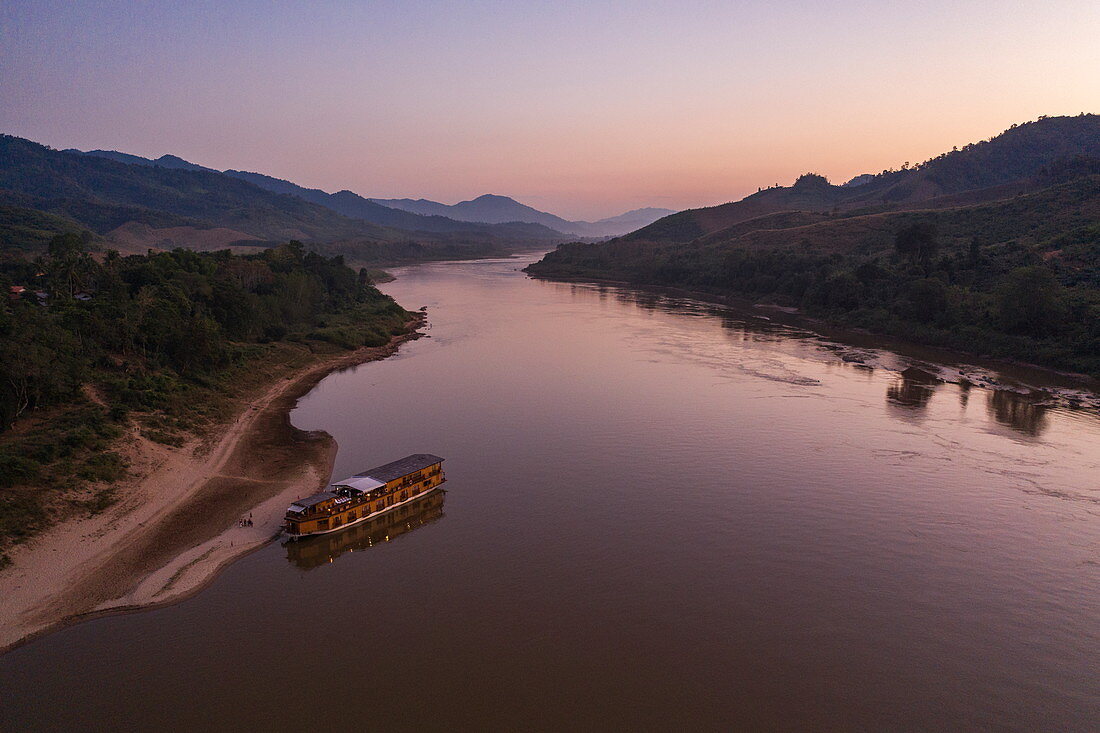 Aerial view of river cruise ship Mekong Sun moored on the sandy bank of the Mekong River at dusk, Ban Hoy Palam, Pak Tha District, Bokeo Province, Laos, Asia