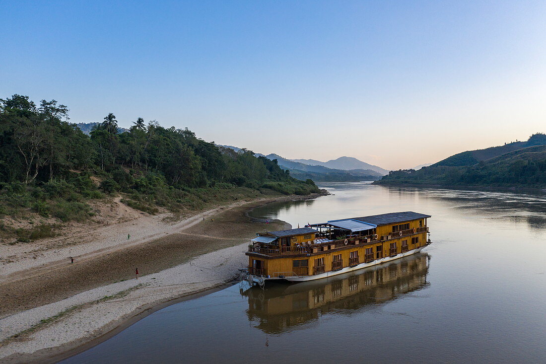 Luftaufnahme von Flusskreuzfahrtschiff Mekong Sun das am sandigen Ufer vom Fluss Mekong festgemacht ist, Ban Hoy Palam, Bezirk Pak Tha, Provinz Bokeo, Laos, Asien