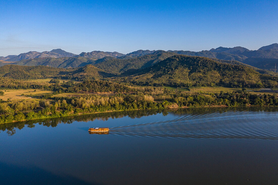 Luftaufnahme von Flusskreuzfahrtschiff Mekong Sun  auf Fluss Mekong mit Bergen dahinter, Bezirk Chomphet, Provinz Luang Prabang, Laos, Asien