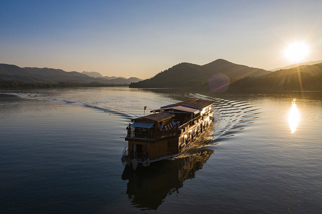 Aerial view of river cruise ship Mekong Sun  on river Mekong with mountains behind at sunset, Chomphet District, Luang Prabang Province, Laos, Asia