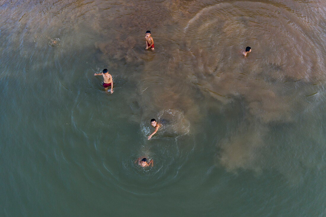 Luftaufnahme von Jungen die in der Nähe des Ufers vom Fluss Mekong schwimmen und spielen, Ban Meung Kai, Provinz Luang Prabang, Laos, Asien