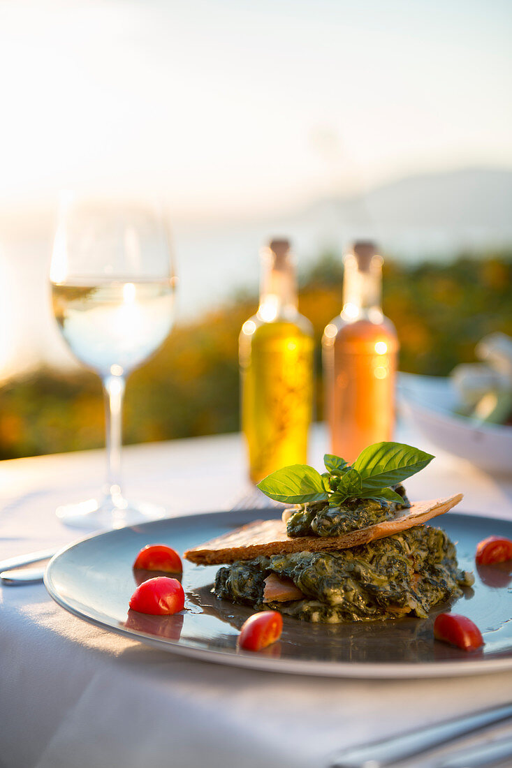 Spanikopita mit Weißwein bei Sonnenuntergang in einem Restaurant in Pefkos, Rhodos, Dodekanes, griechischen Inseln, Griechenland, Europa
