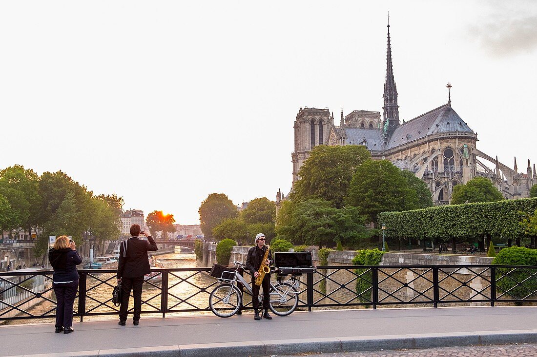 Frankreich, Paris, Saxophonist auf der Brücke des Erzbischofs und Notre Dame de Paris